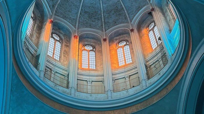 Das Bild zeigt eine Kuppelhalle mit hohen Fenstern und einem kreisförmigen Balkon.