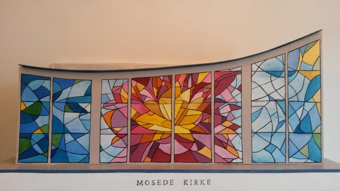 Stained glass vindues i kirke med farverige mønstre og teksten