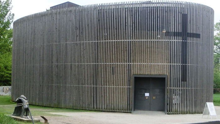 Das Bild zeigt eine moderne Kirche mit Holzwänden und einem großen Kreuz.