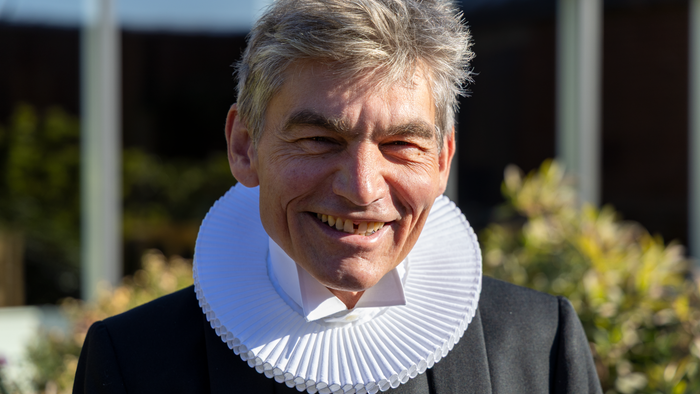 Mand med kravekrans smiler.