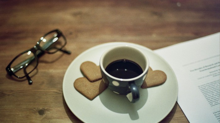 Briller, kaffe og småkager på et træbord