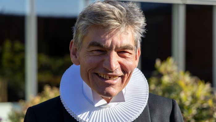 Mand med kravekrans smiler.