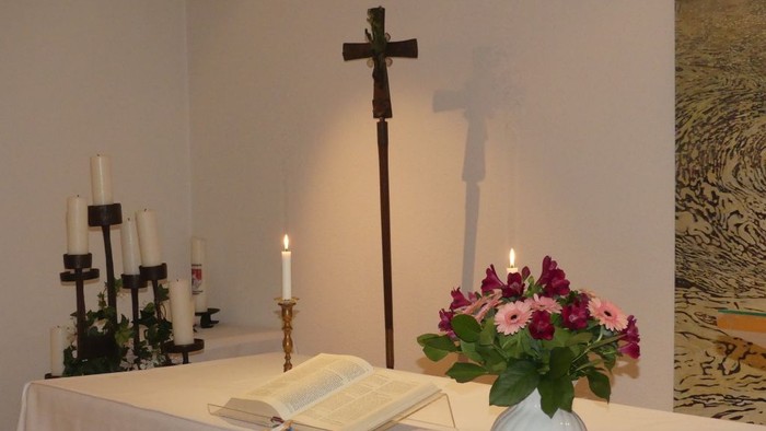 Elegante Altar-Anordnung mit Kerzen, einem offenen Buch, Blumen und einem markanten Kreuz.