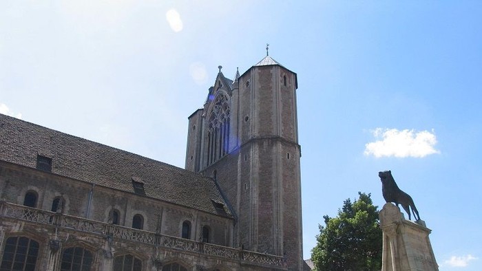Das Bild zeigt eine große gotische Kathedrale mit einem hohen Turm und einem klaren blauen Himmel.