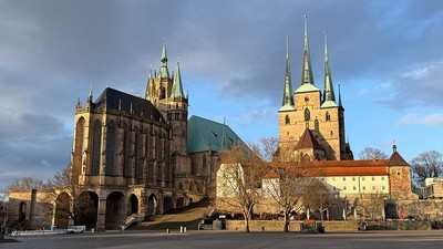 Historischer Kathedralenkomplex mit Zwillingstürmen und gotischer Architektur unter einem teilweise bewölkten Himmel.
