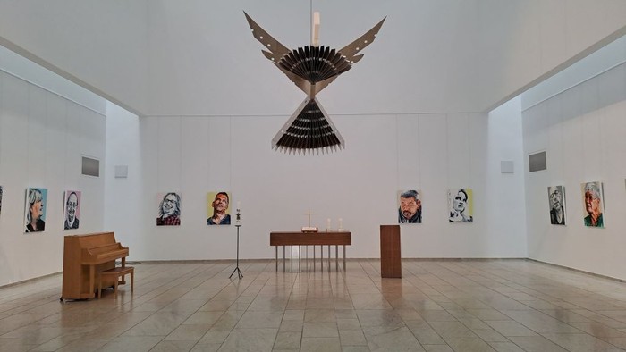 Moderne Kunstgalerie mit Porträts, einem Flügel und einer auffälligen hängenden Vogelskulptur.