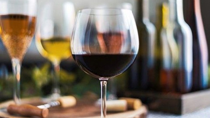 Elegante vinglas med rød- og hvidvin, ledsaget af propper og flasker på en rustik træplade.