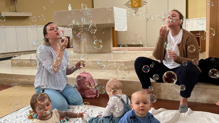 To børn og to voksne sitter på en bunad og blæser boble.