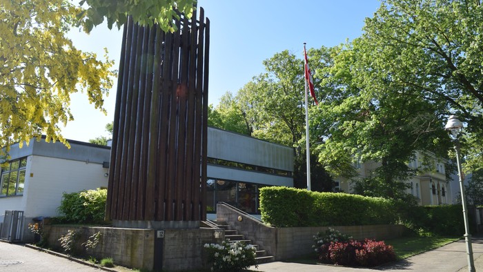 Moderne bygning med høj trækonstruktion, amerikansk flag og velplejet grønne områder.