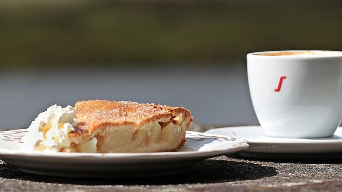 Ein Stück Kuchen und eine Tasse Kaffee auf einem Tisch am Wasser