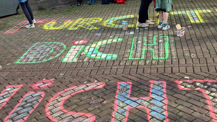 Bunte Kreidemalerei mit den Worten „BRIGHT“ und „NIGHT“ auf einem Backsteinpflaster während einer Open-Air-Veranstaltung.