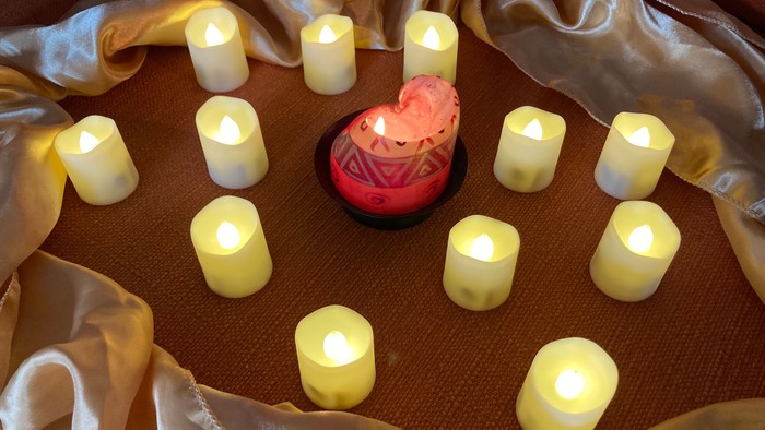 Mehrere angezündete Kerzen auf einem Tischtuch mit goldener Decke