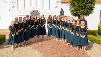 En gruppe kvinder i matchende sorte kjoler poser formelt foran en hvid kirkebygning.