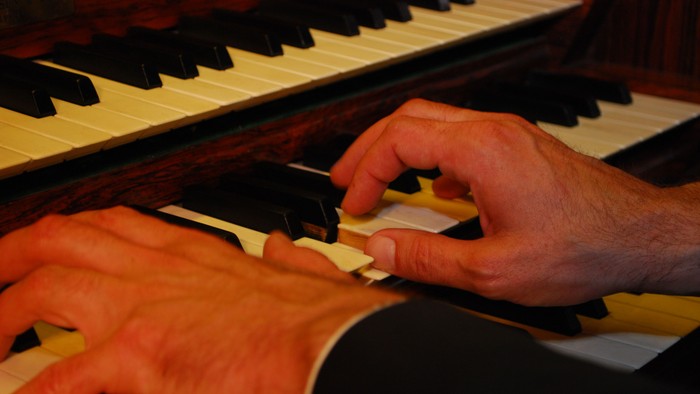 Hände spielen Klavier, Notenblätter sichtbar