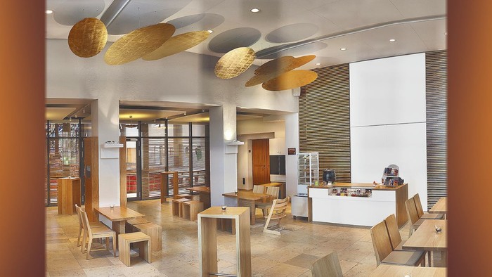 Modernes Café mit Holzmöbeln, hängenden Leuchten und einem offenen Gemeinschaftsbereich.