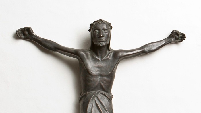 Eine Bronzestatue eines Mannes mit ausgebreiteten Armen an einer Wand