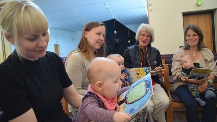 En gruppe kvinder med små børn i en indendørs lokalitet