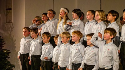 En gruppe unge drenge i formelt tøj, der synger sammen på en scene under en optræden.