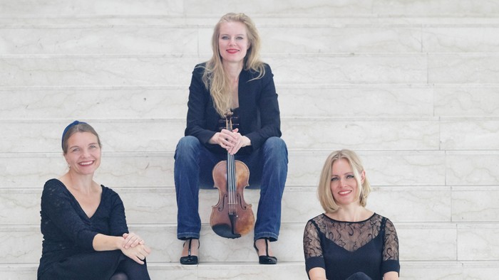 En trio musikere poser med en cello og en violin på en trappe.