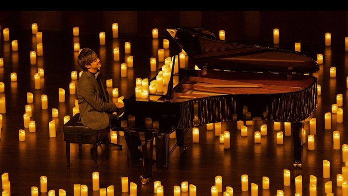 Pianist am Klavier im Altarraum der Apostel-Paulus-Kirche, umgeben von Lichtern am Boden