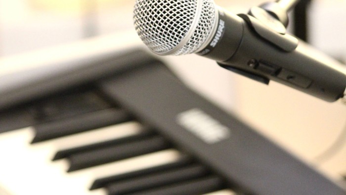 Ein Mikrofon steht vor einem Keyboard.