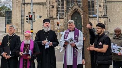 Religiöse Führer und Aktivisten versammeln sich vor einer Kirche, halten Schilder und Bücher in einer öffentlichen Demonstration.