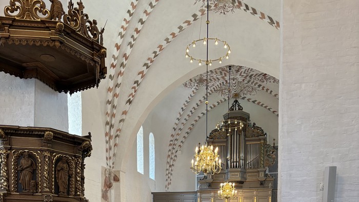 Indgang til en stor kirke med høje vægge og orgel.
