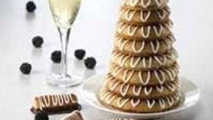 En kage med kager på en kagestand og en glas vin.