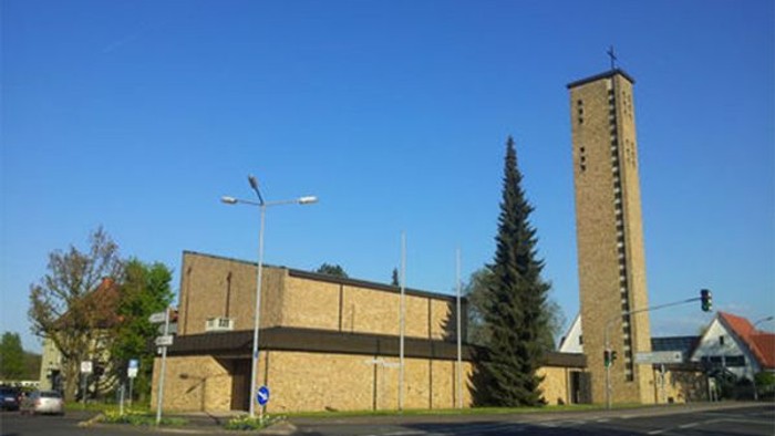 Moderne Kirchengebäude mit hohem Backsteinturm und klarem blauem Himmel im Hintergrund.