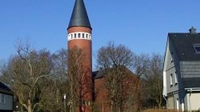 Ein rotes Backsteingebäude mit schwarzer Spitze und ein Auto davor.