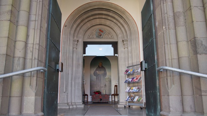 Kircheneingang mit offenen Türen und ausgestellten religiösen Gegenständen.