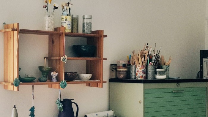 Charmante Holzregale halten Kunstmaterialien, Vasen und Dekorationsgegenstände vor einer hellen Wand.