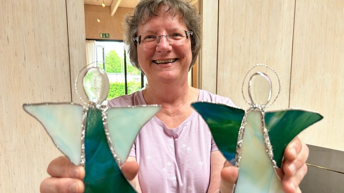 Eine Frau hält zwei bunte Glasengel in den Händen