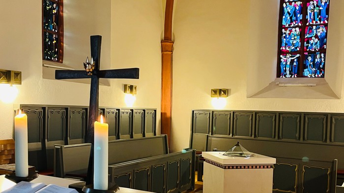 Innenraum einer Kirche mit Altartisch, Kerzen und Bänken