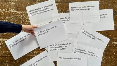 Hand hält Notizen mit deutschem Feedback zu Diskussionen über sexualisierte Gewalt und institutionelle Reaktionen.