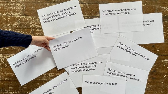Hand hält Notizen mit deutschem Feedback zu Diskussionen über sexualisierte Gewalt und institutionelle Reaktionen.