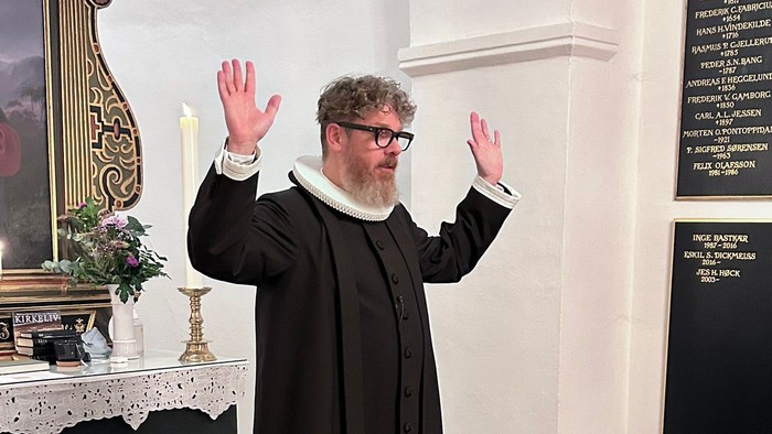 Mand i svart kapittel i kirke.