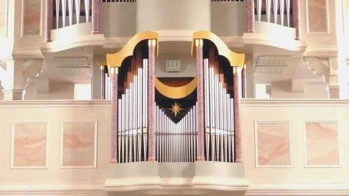 Elegante Pfeifenorgel mit goldenen Akzenten und mehreren Reihen polierter Pfeifen in einem prächtigen Ambiente.