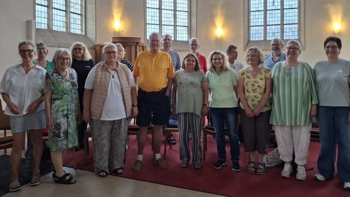 Gruppe von Menschen, die gemeinsam in einer hell erleuchteten Kirche oder Kapelle posieren.