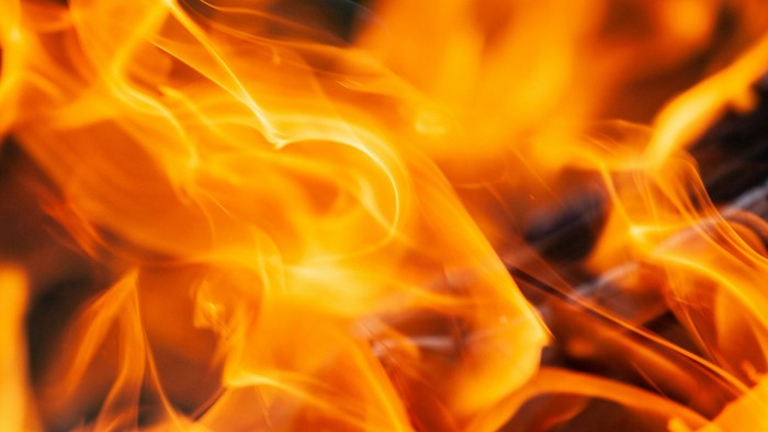 Lebhafte Flammen tanzen und wirbeln in intensiven, feurigen Orange- und Gelbtönen.