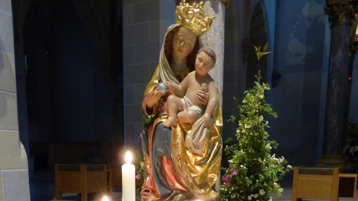 Religiöse Statue mit Kerzen und Blumen in Kirche