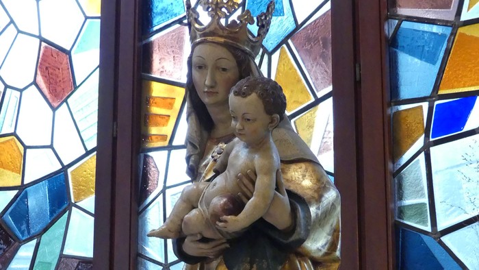 Heilige Muttergottes Statue vor buntem Kirchenfenster