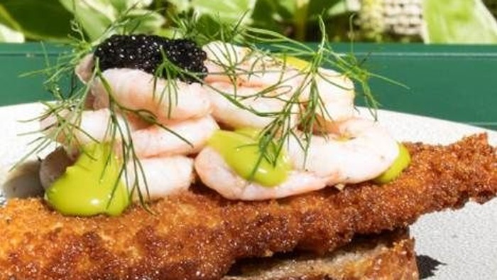 Knusprigt stegt fisk toppet med kaviar, rejer, citron og garneret med friske urter på ristet brød.