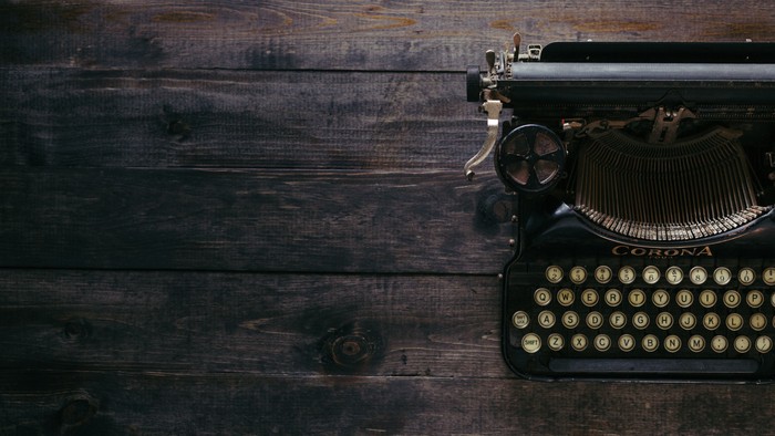 Ein altmodischer Schreibmaschine auf einem dunklen Holztisch.