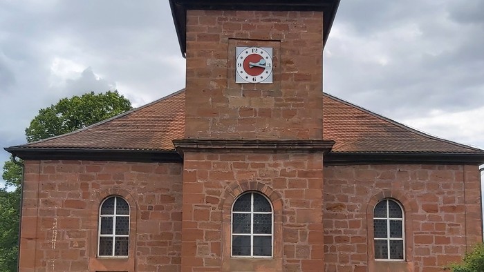 Rotes Backsteingebäude mit einem Turm und Rundbogenfenstern.