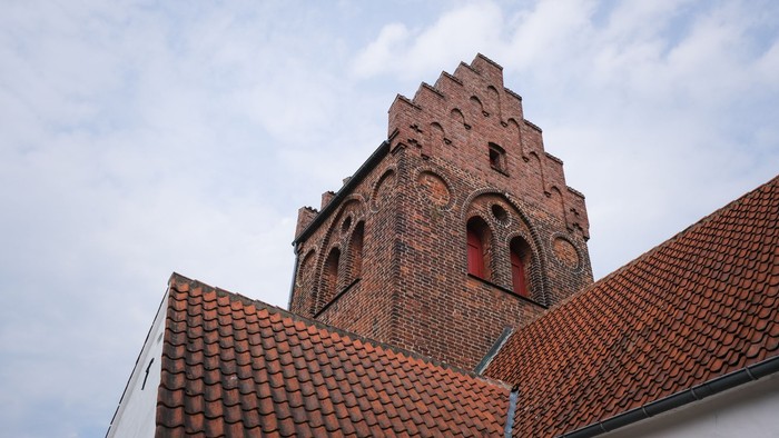 Gammel teglkirke med spiret mod himlen