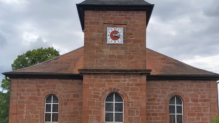 Rotes Backsteingebäude mit einem Turm und Rundbogenfenstern.