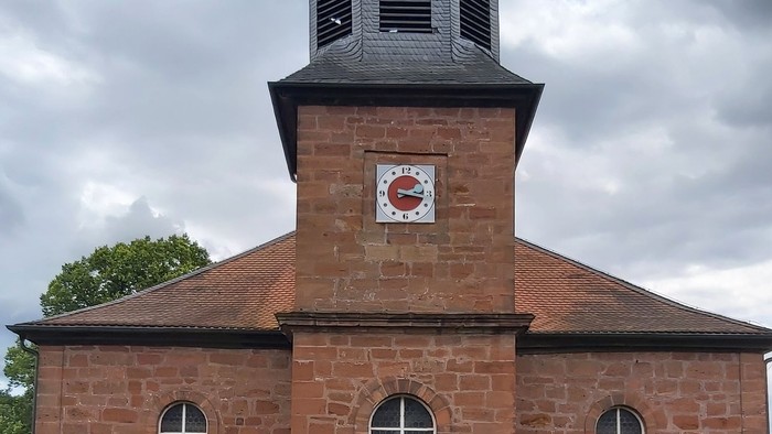 Rotes Backsteingebäude mit einem Turm und Rundbogenfenstern.