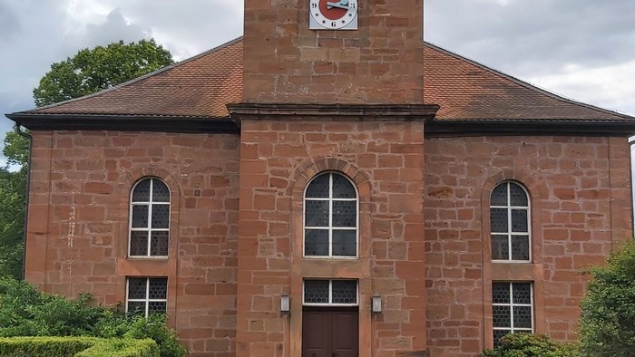 Rotes Backsteingebäude mit einem Turm und Rundbogenfenstern.