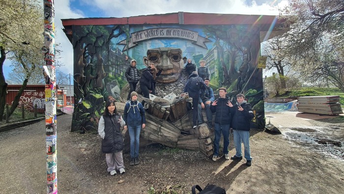 En gruppe mennesker poser foran et stort muralmaleri af en bulldogger.